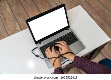 Modern Slavery Concept. Above View Of A Man Hands Typing On A Laptop And Tied With The Charging Cable.