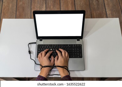 Modern Slavery Concept. Above View Of A Man Hands Typing On A Laptop And Tied With The Charging Cable.