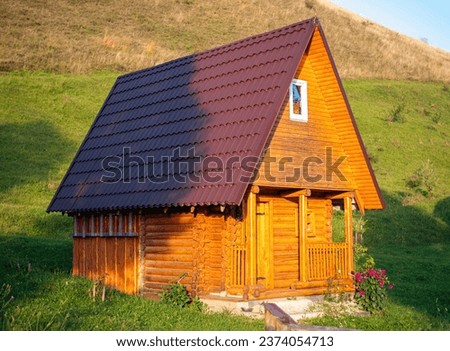 Modern small wooden house forest scenic view in Carpathian mountains, Transcarpathia region, Ukraine, Europe. Perfect tiny rental home apartments for travelers with green grass lawn blooming flowers.