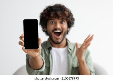 Modern Smartphone With Black Blank Screen In Excited Indian Guy Hand, Happy Hindu Man Showing Mobile Phone And Gesturing, Recommending Nice Mobile Application, Mockup, Closeup Photo