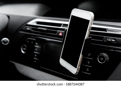 Modern smartphone device gadget mounted on phone holder at car dashboard. 