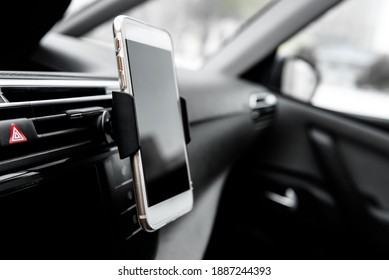 Modern smartphone device gadget mounted on phone holder at car dashboard. 