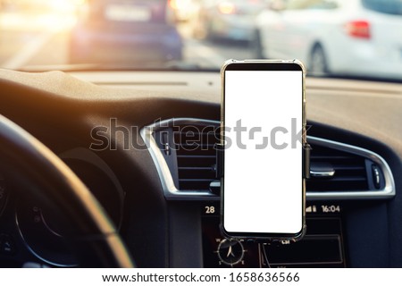 Modern smartphone device gadget mounted on phone holder at car dashboard. Mock-up white screen isolated template. Copyspace for text . Vehicle interior cockpit view. Traffi jam info app