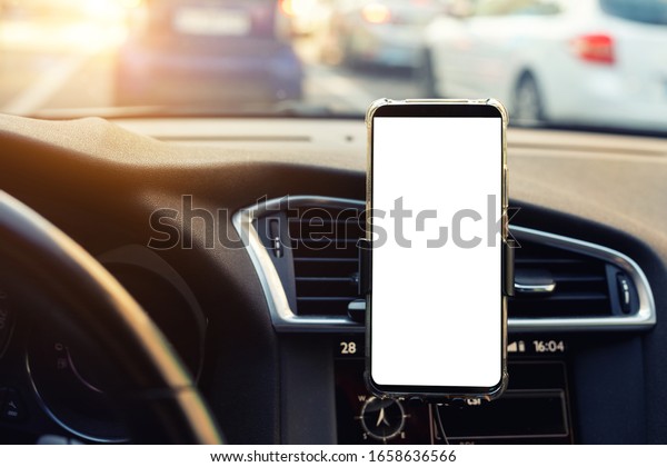 Modern\
smartphone device gadget mounted on phone holder at car dashboard.\
Mock-up white screen isolated template. Copyspace for text .\
Vehicle interior cockpit view. Traffi jam info\
app