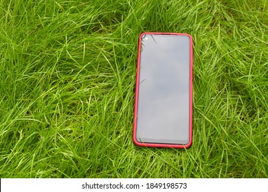 Modern smartphone with a red case on green fresh grass.