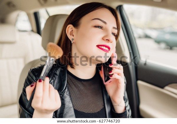 Modern\
smiling girl in car talk on phone and\
make-up