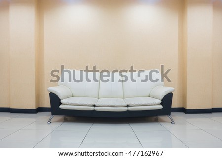 modern sofa  black and white color stand on the living room and orange wall background with ceiling lights on top.