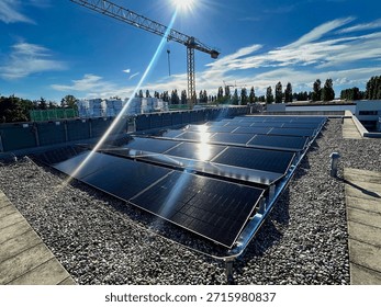 Modern solar panel array on a gravel flat roof of a commercial building under a bright sun. Renewable energy and sustainable construction.