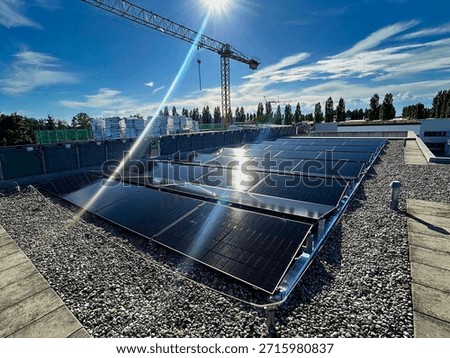 Modern solar panel array on a gravel flat roof of a commercial building under a bright sun. Renewable energy and sustainable construction.
