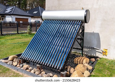 A modern solar pressure collector to heat domestic hot water, standing in front of the house on the lawn. - Shutterstock ID 2150628423