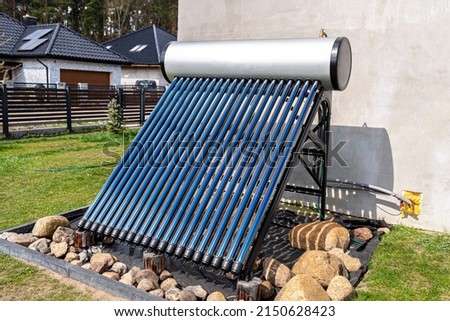 A modern solar pressure collector to heat domestic hot water, standing in front of the house on the lawn.