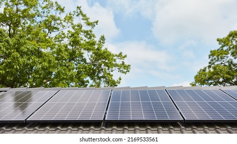 Modern solar system on roof of family house in front of a green tree and a blue sky - Shutterstock ID 2169533561