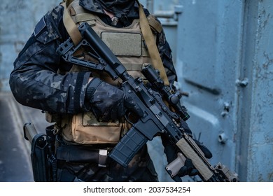 Modern Soldier In Black Multicam Uniform With Rifle, Urban Background 