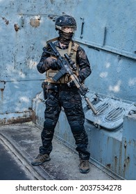 Modern Soldier In Black Multicam Uniform With Rifle, Urban Background 