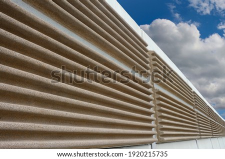 A modern soundproof wall with cloudy sky in background