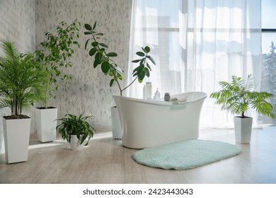 Modern spacious bathroom with tropical decor and sunlit window. Front view of lovely bathroom with freestanding bathtub, numerous of houseplants and fluffy rug on floor. Design, interior concept. - Powered by Shutterstock