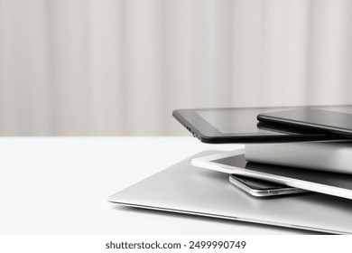 Modern stack of laptop tablet and smartphone on white desk with copy space, minimal home office technology composition for digital communication, productivity and remote work