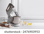 Modern stand mixer and ingredients for dough on white table indoors. Space for text