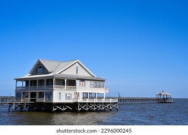 A modern stilt house with a pier and gazebo built on pilings in Lake Pontchartrain.