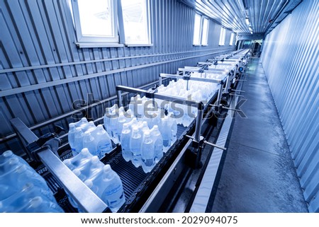 Modern strapping and transporting machine for packaging line at beverage plant.