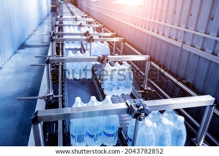 Modern strapping and transporting machine for packaging line at beverage plant.