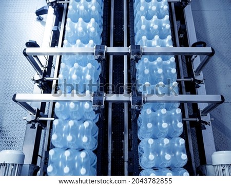 Modern strapping and transporting machine for packaging line at beverage plant.