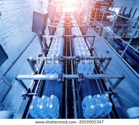 Modern strapping and transporting machine for packaging line at beverage plant.