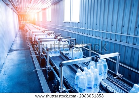 Modern strapping and transporting machine for packaging line at beverage plant.