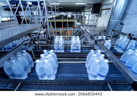 Modern strapping and transporting machine for packaging line at beverage plant.