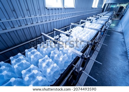Modern strapping and transporting machine for packaging line at beverage plant.