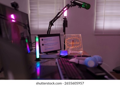 Modern streaming desk setup featuring computer monitor microphone RGB lighting headphones and subscribe sign for live stream content creation