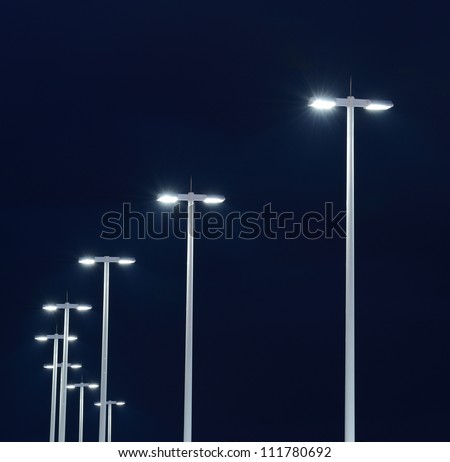 Modern street lights illuminated at night against a dark sky