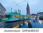 A modern streetcar dashing by the corner of Market Square in Halle (Saale) at rush hour and landmark Red Tower standing out before the church on a drizzling morning, in Saxony-Anhalt, Germany, Europe