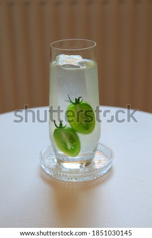 Modern style Cocktail with clear ice spear, green tomato water, vodka, lime, cucumber and bitters following state of the art mixology trends