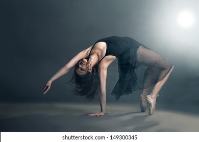 Modern style dancer posing on a studio grey background in fog - Powered by Shutterstock