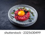 Modern style gourmet tartar raw from beef filet with egg and capers served as close-up on a Nordic design plate with copy space 