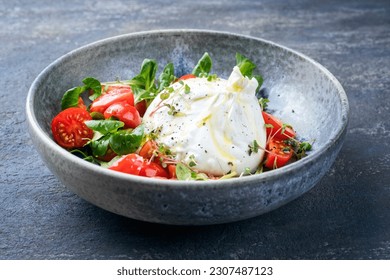 Modern style Italian Apulia Burrata cow milk cheese made from mozzarella and cream served with tomato and corn salad as close-up in ceramic Nordic design bowl - Powered by Shutterstock