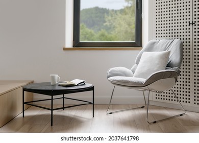 Modern style of living room, home interior. House design with furniture, minimalistic apartment. Comfortable chair near window, armchair decoration. Contemporary indoor with table.