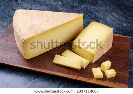 Modern style traditional aged mountain cheese of the Alps offered as piece and slice on a wooden design board 