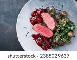 Modern style traditional fried dry aged angus beef filet medaillons natural with mushrooms, kalette and cranberry relish served as top view on a design plate with copy space left