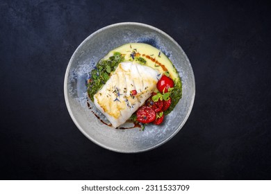 Modern style traditional fried skrei cod fish filet with mashed potato cream and coriander lime relish served as top view on Nordic design plate with copy space 