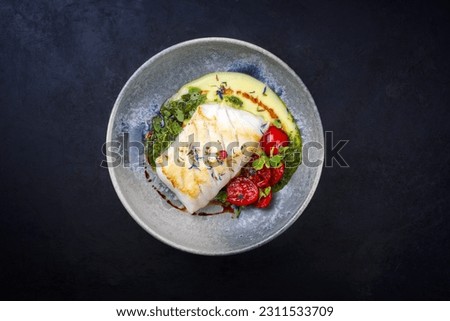 Modern style traditional fried skrei cod fish filet with mashed potato cream and coriander lime relish served as top view on Nordic design plate with copy space 