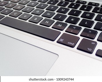 A modern, stylish computer keyboard, with the focus on the “cmd” and “alt” keys. The flat trackpad can be seen in the frame