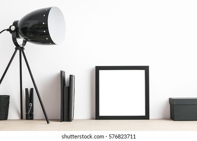 Modern and stylish interior with empty frame, lamp and houseplant. Mock up.