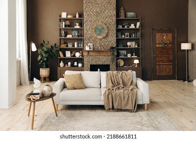 Modern stylish living room with large windows and beige sofa on the backgroung of brown wall with fireplace, shelving with books and decor, and potted plants. Cozy chalet interior. Empty space. - Shutterstock ID 2188661811
