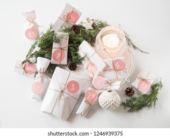 Modern and stylish self-made advent calendar - beautiful white gifts with pink numbers on a white background with candle, christmas baubles, fir branches and cones - beautiful christmas decoration - Powered by Shutterstock