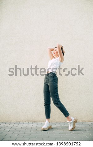 Modern stylish woman in big white sneakers posing against a wall. Fooling around