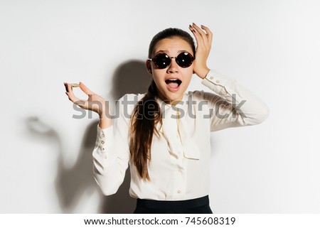 a modern successful girl in black sunglasses holds a gold bitcoin in her hand and looks very surprised