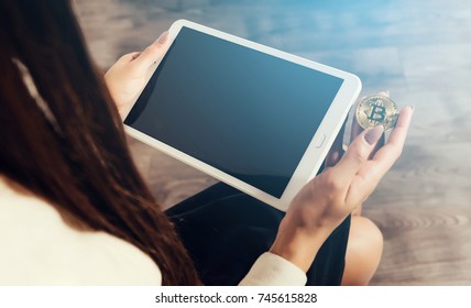 modern successful girl holds a gold bitcoin and a tablet in her hands - Shutterstock ID 745615828