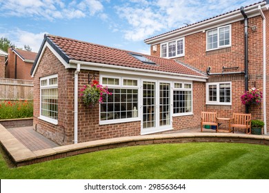 Modern Sunroom external / Modern Sunroom or conservatory extending into the garden, surrounded by a block paved patio - Shutterstock ID 298563644